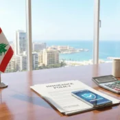 Modern insurance broker office desk in Beirut featuring a Lebanese flag, a stack of insurance policy papers, and a smartphone displaying a digital protection shield.